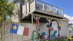 Une maison avec une terrasse en bois, un espace salon extérieur et un drapeau.