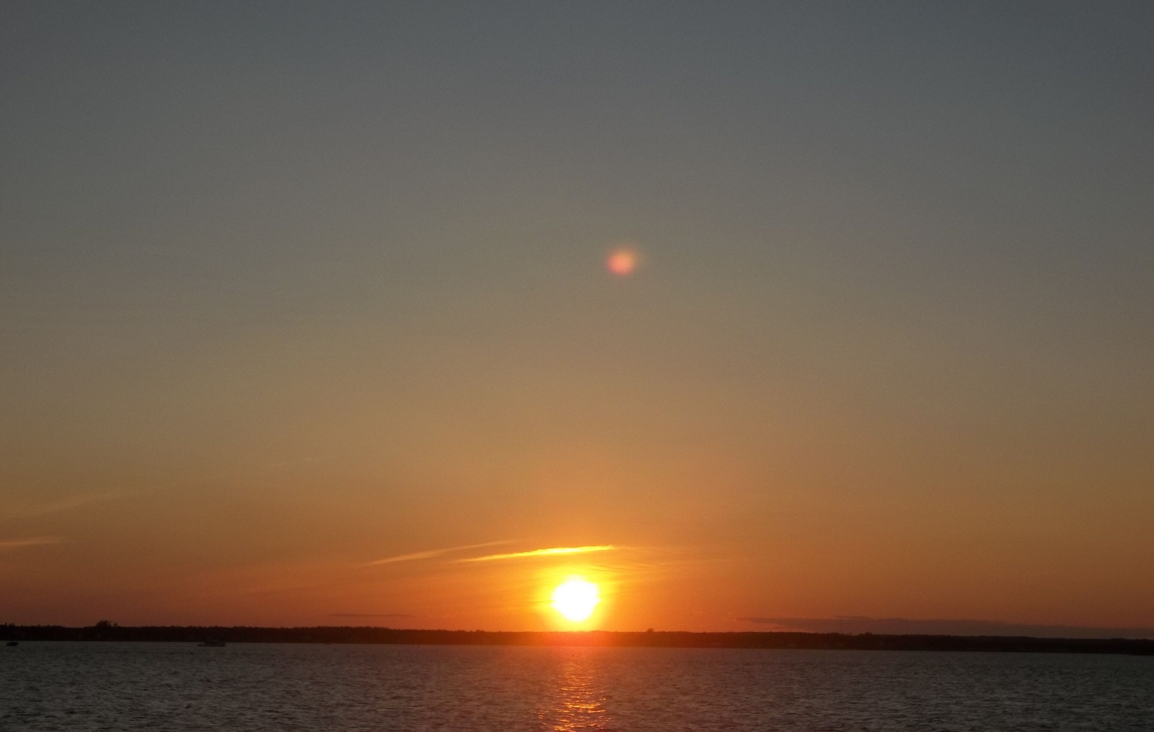 A sunset over a calm body of water with a clear horizon.