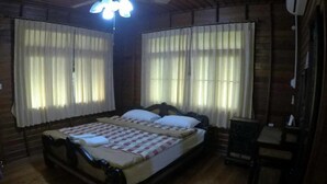 A wooden room with a bed, a desk, and a chair. - Hugphaeng Garden (Ban Phaeng)