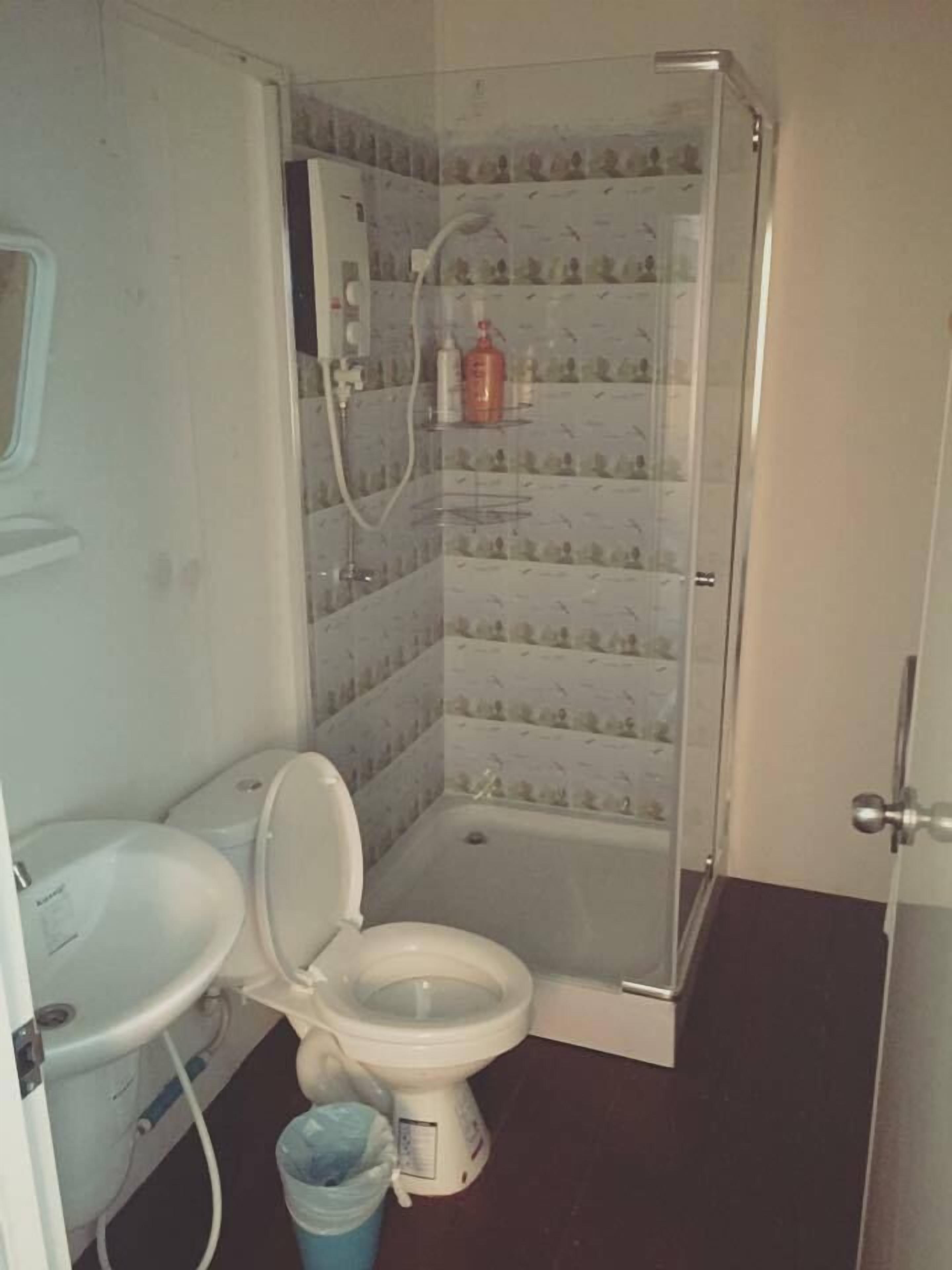 Een kleine badkamer met toilet, wastafel en douche.