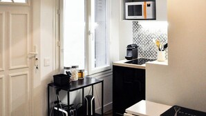 A compact kitchen with a microwave, a small countertop, and a cart with bags. - Charming duplex in Montmartre (Paris)