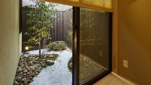 A room with a sliding glass door leading to a garden with a tree and gravel path. - Rinn Miyagawacho Tsubaki (Kyoto)