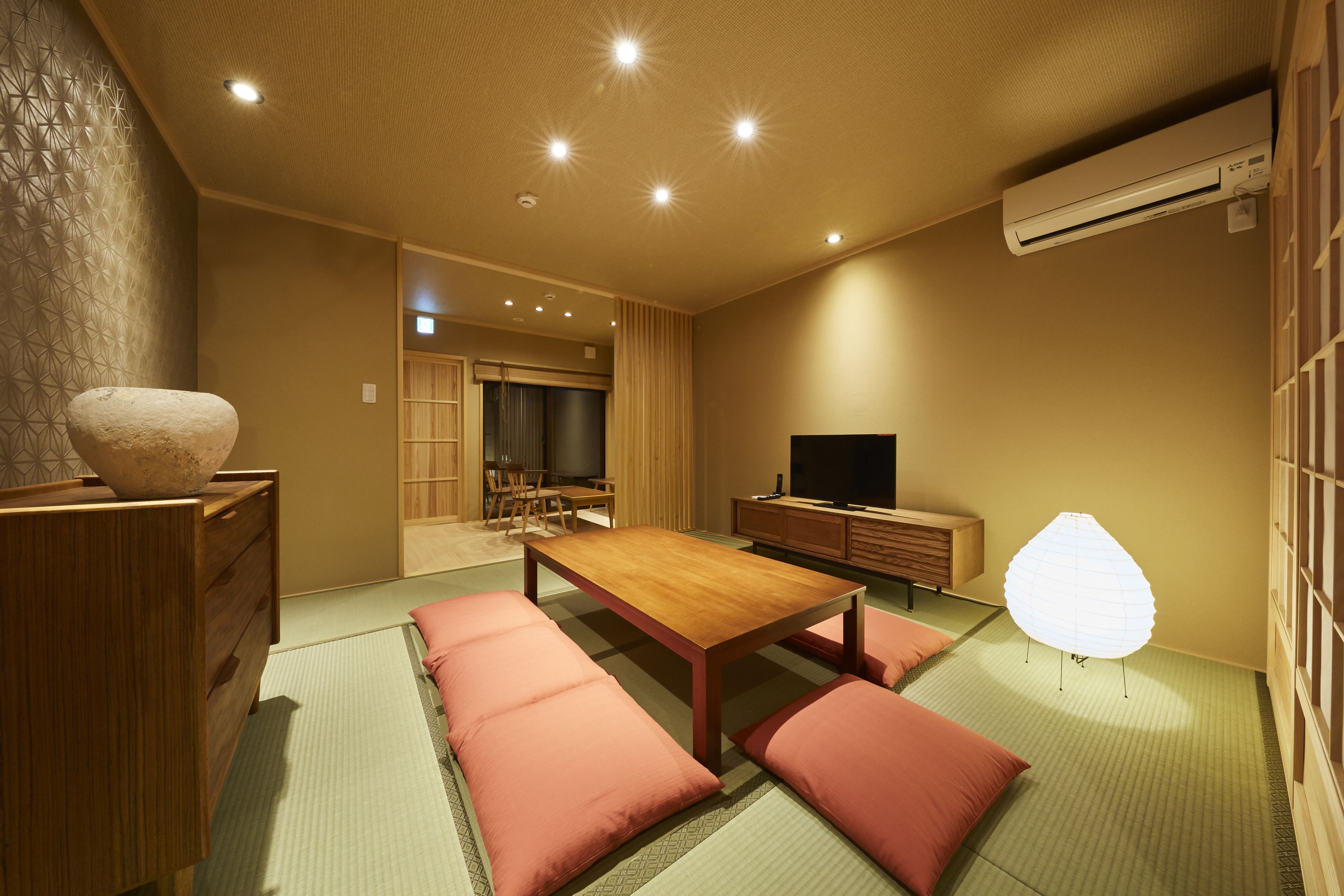 A traditional Japanese-style room with tatami flooring, a low wooden table, and a television.