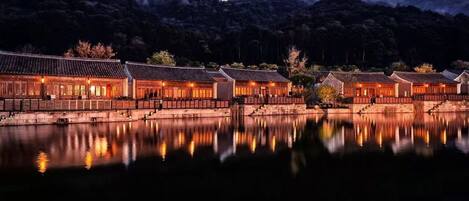 A traditional building with a reflection in the water, surrounded by mountains.