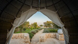 An outdoor view through a covered area with stone walls and a gravel path leading to a garden.