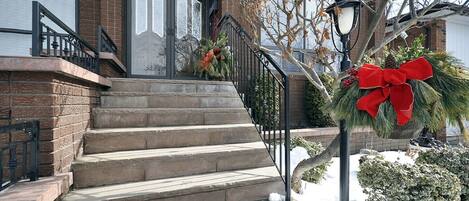 Un immeuble résidentiel à la façade en briques, portant le numéro « 21 » et dont un escalier mène à l’entrée.