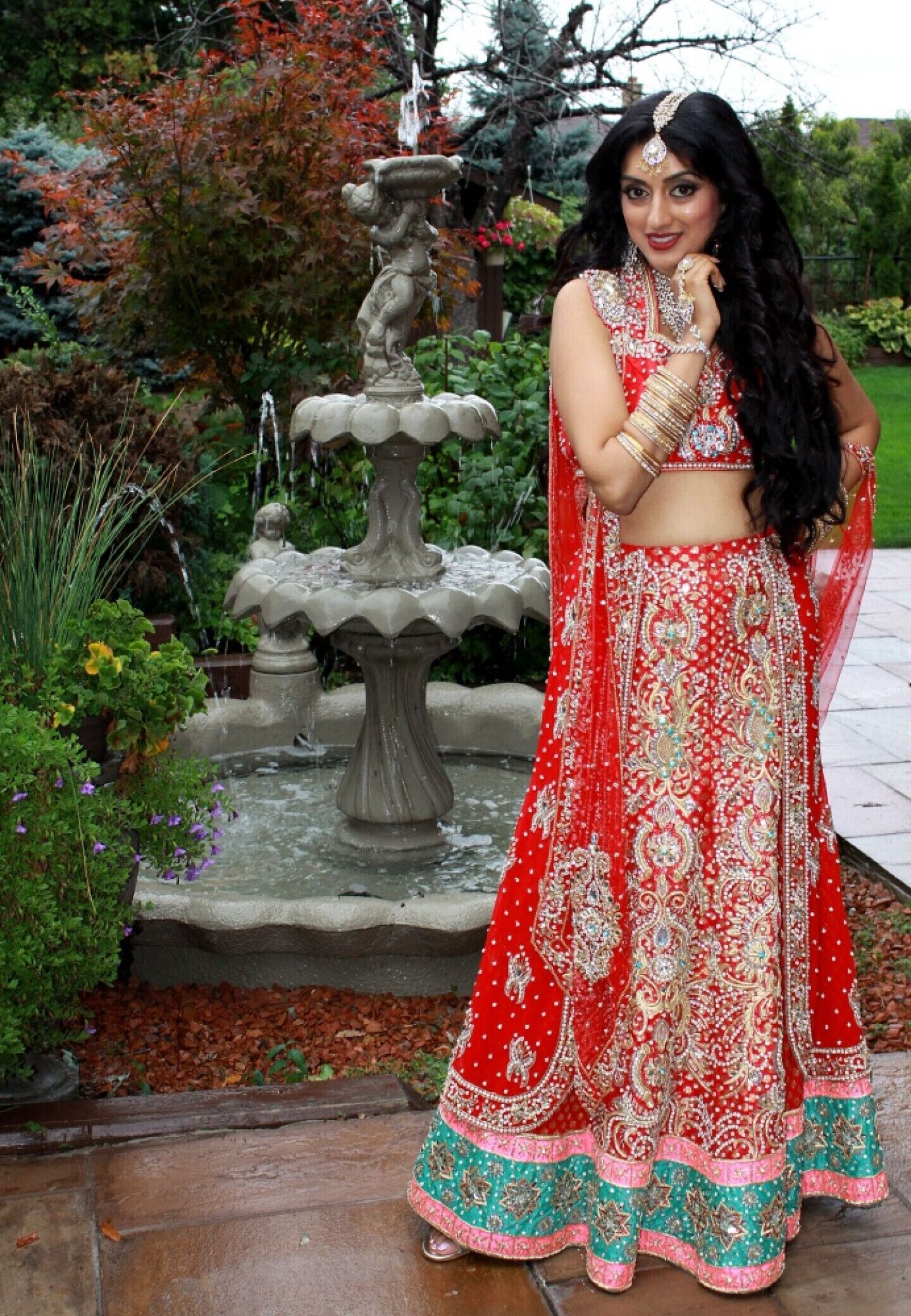 Una persona vestida con un traje tradicional rojo y dorado frente a una fuente.