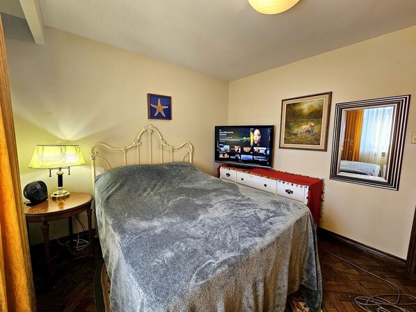 A bedroom with a bed, a TV, a lamp, and a dresser.