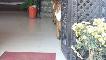 A doorway with a red mat, a potted plant, and a decorative metal gate.
