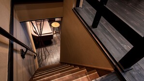 A wooden staircase with a handrail, leading to a room with a round table and chairs. - Rinn Manjuji (Kyoto)