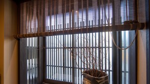 A room with a large window, a woven blind, and a potted plant. - Rinn Manjuji (Kyoto)