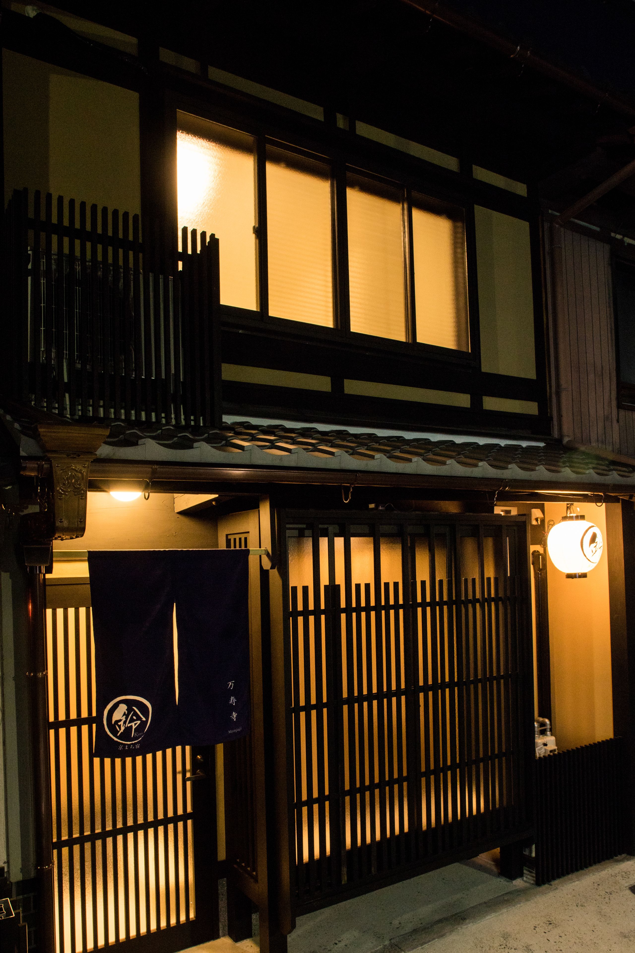 Un edificio japonés tradicional con fachada de madera, tejado de tejas y un farol.