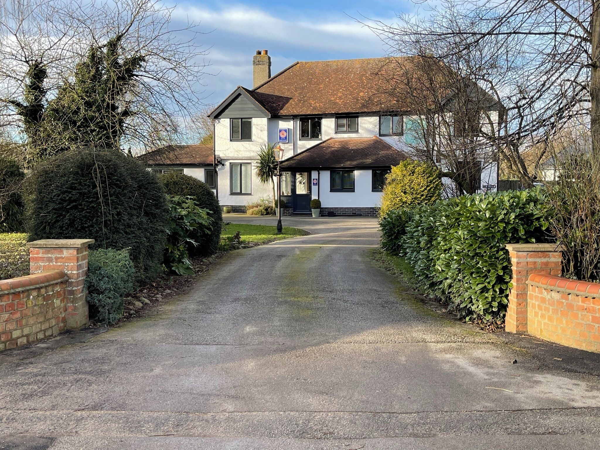A two-story house with a paved driveway leading to a front door.