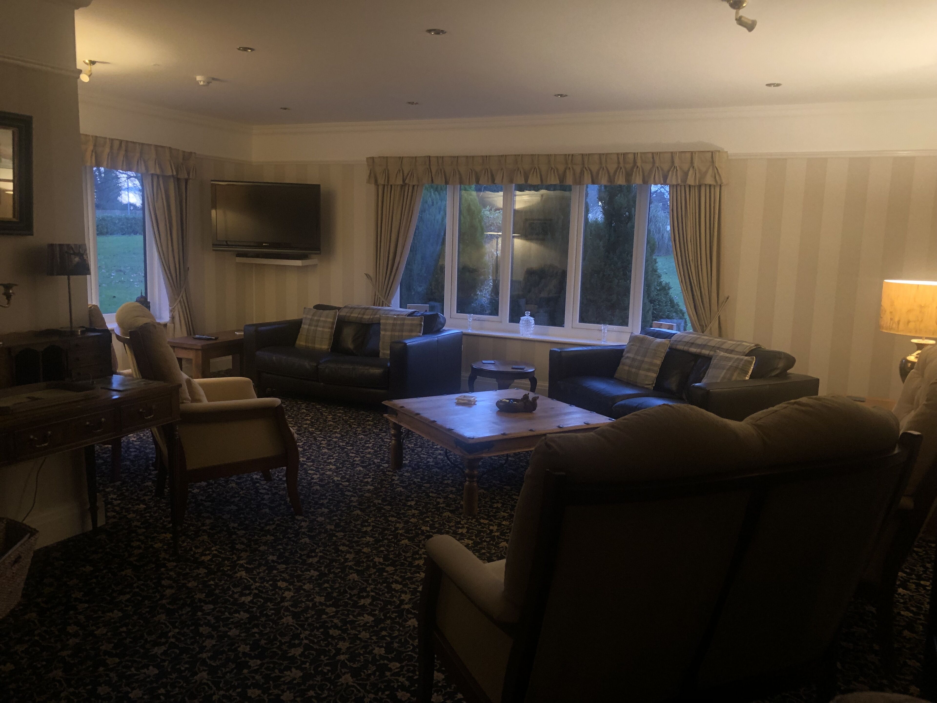 Een woonkamer met een bank, fauteuils, een salontafel en een televisie.