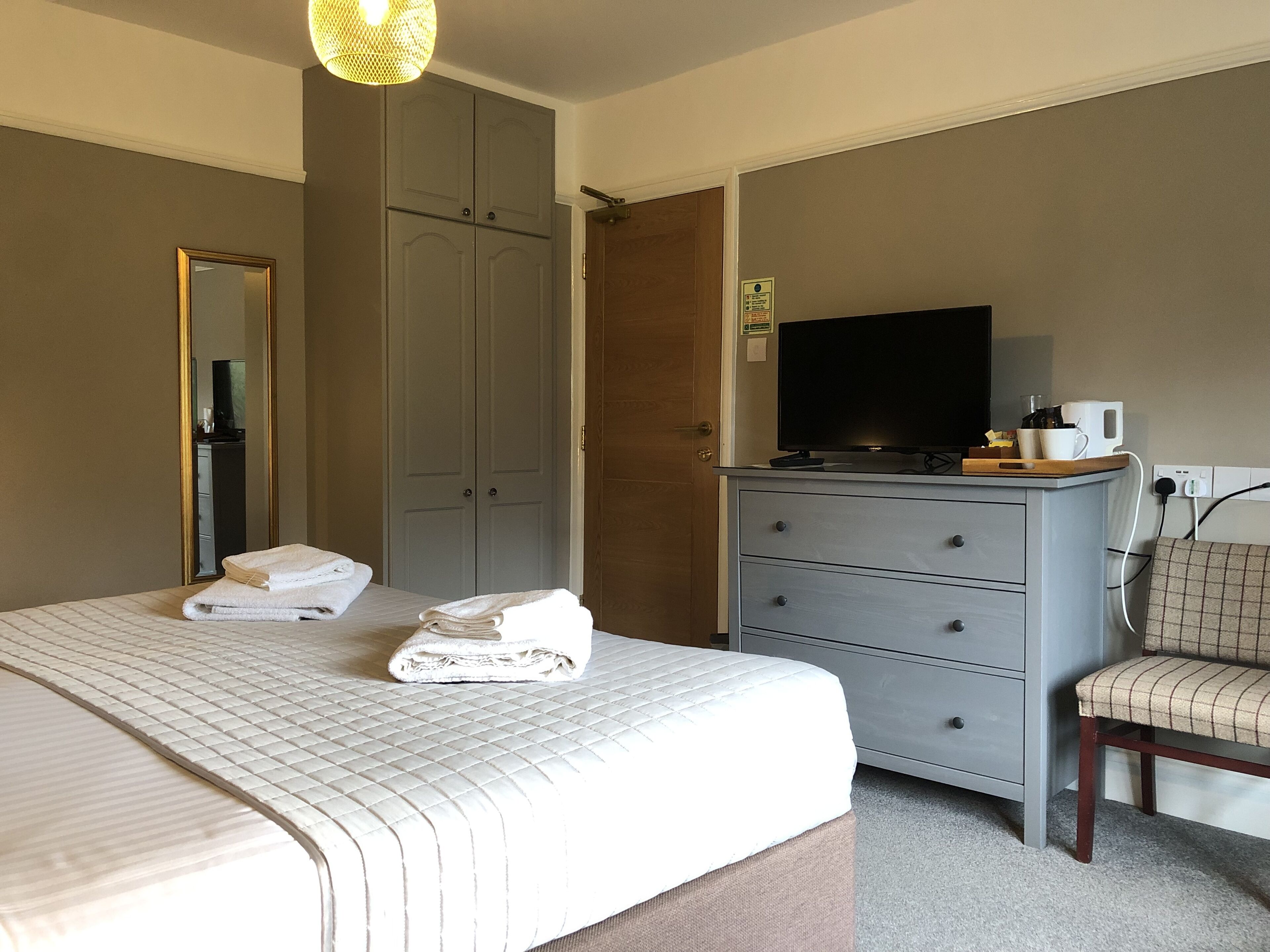 A hotel room with a bed, a dresser, a television, and a chair.