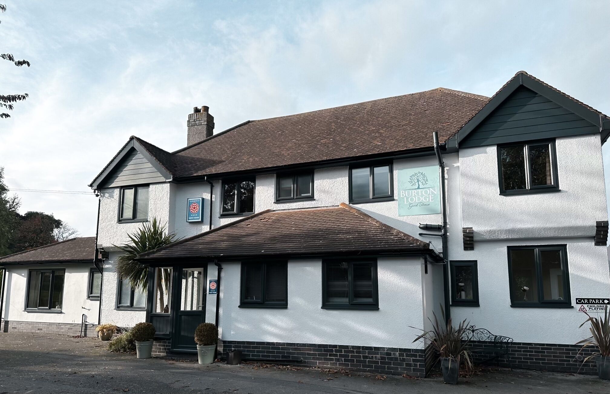 A two-story building with a sign for Burton Lodge Guest House.