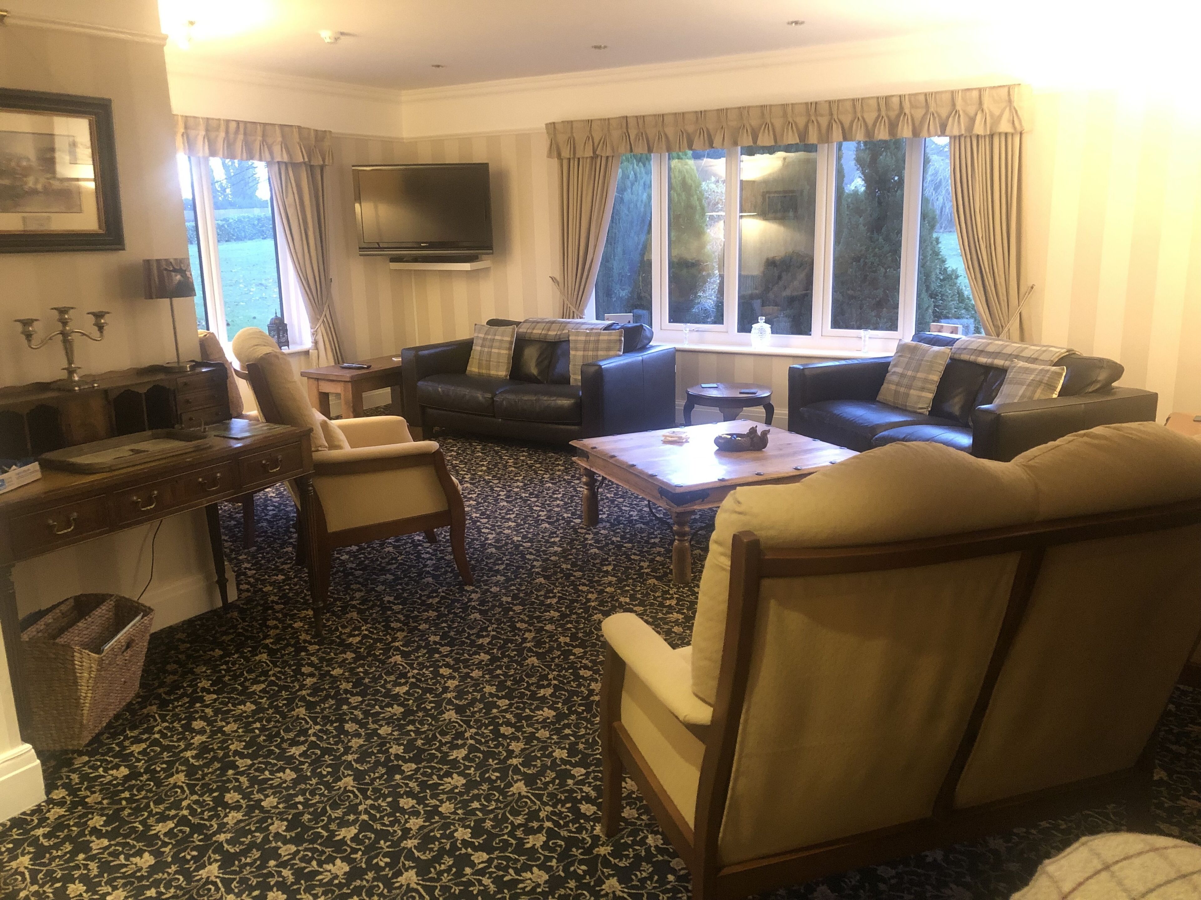 Un salón con sofá, sillones, una mesita de centro, televisor y vistas al exterior.