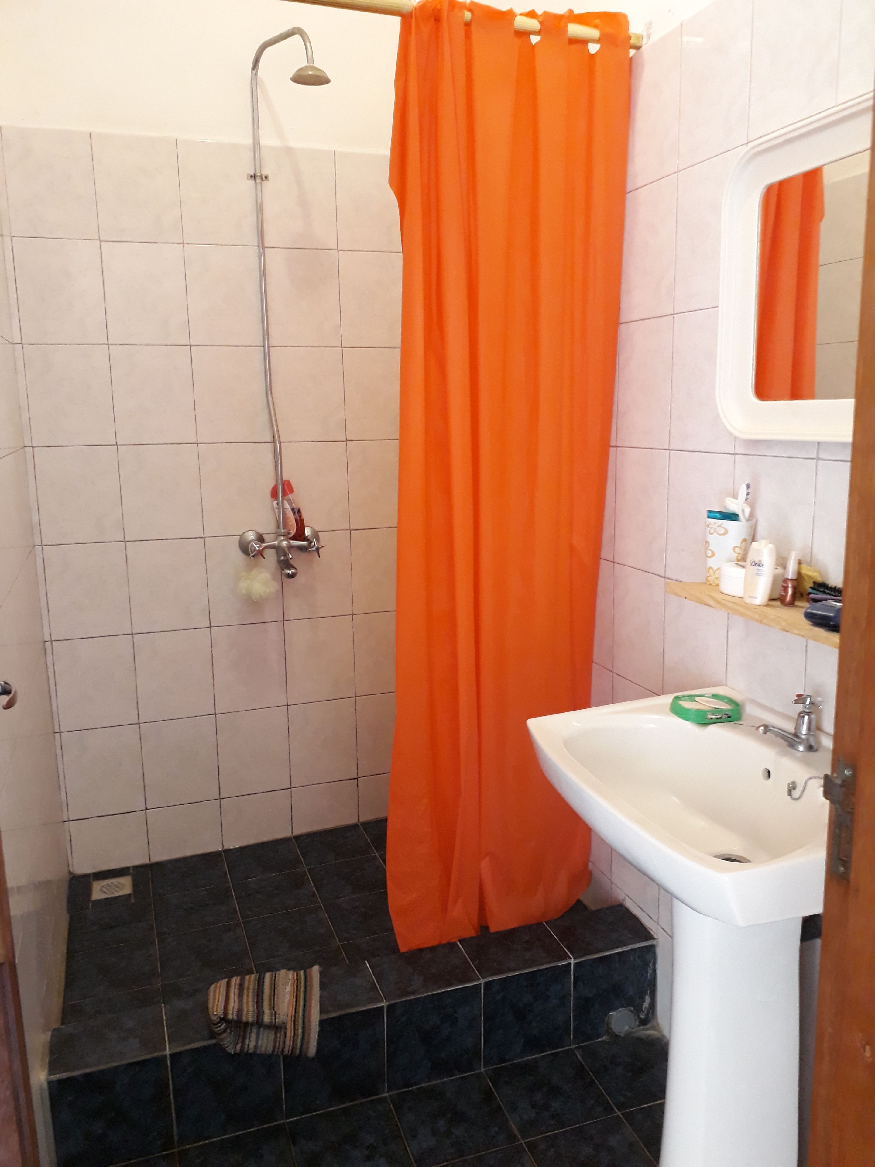 Un baño con ducha, lavamanos y espejo.