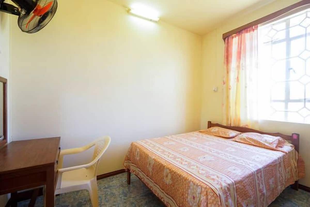 A bedroom with a bed, a desk, and a chair.
