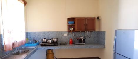 A compact kitchen with a sink, stove, microwave, and cabinets.