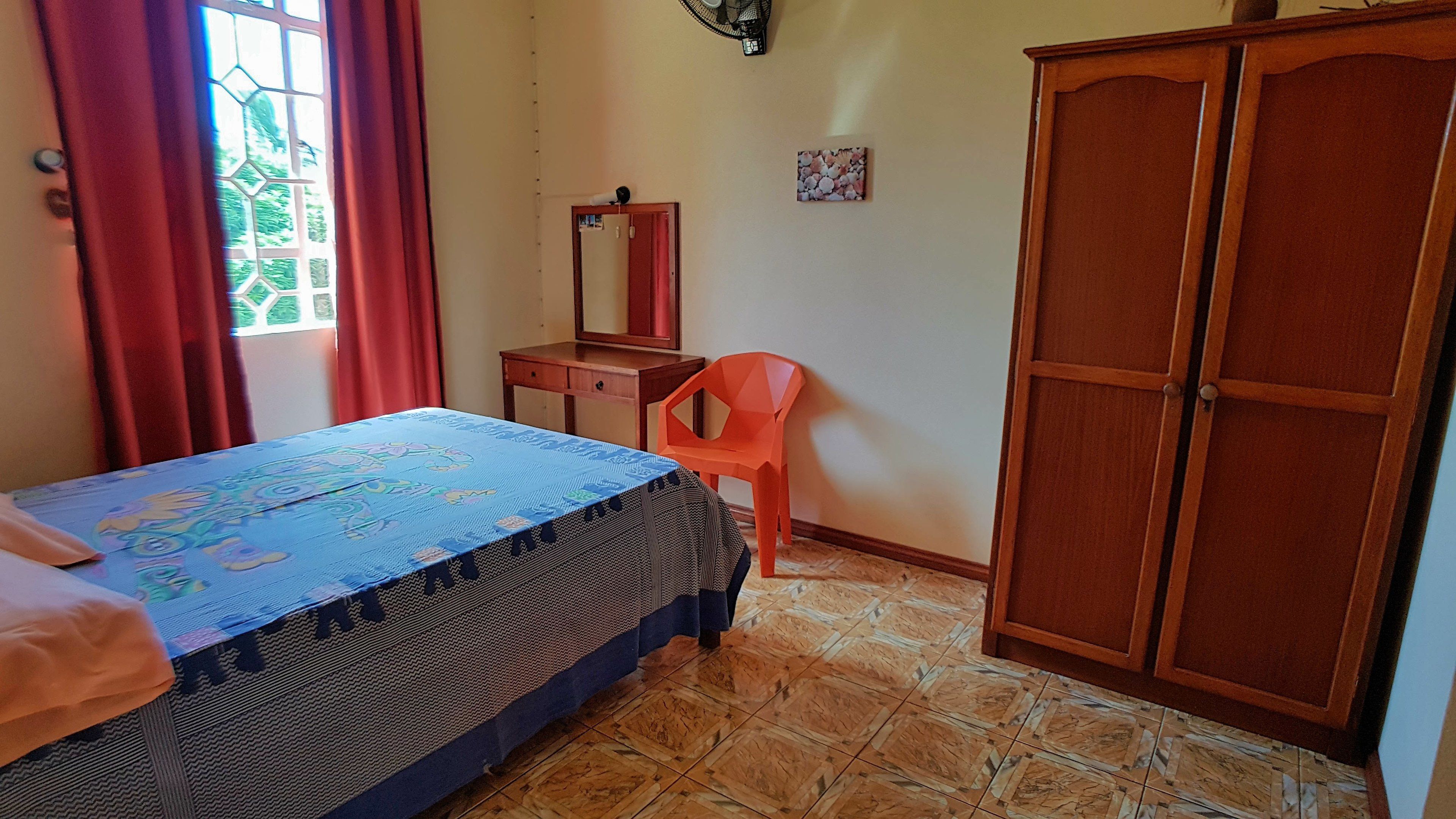 A bedroom with a bed, a desk, a chair, and a wardrobe.