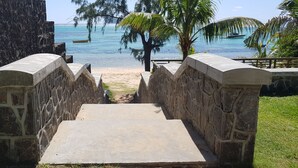 Una escalera de piedra que lleva a una playa con palmeras y un bote en el agua.