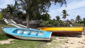 Two boats on a sandy beach with a stone staircase and palm trees in the background.