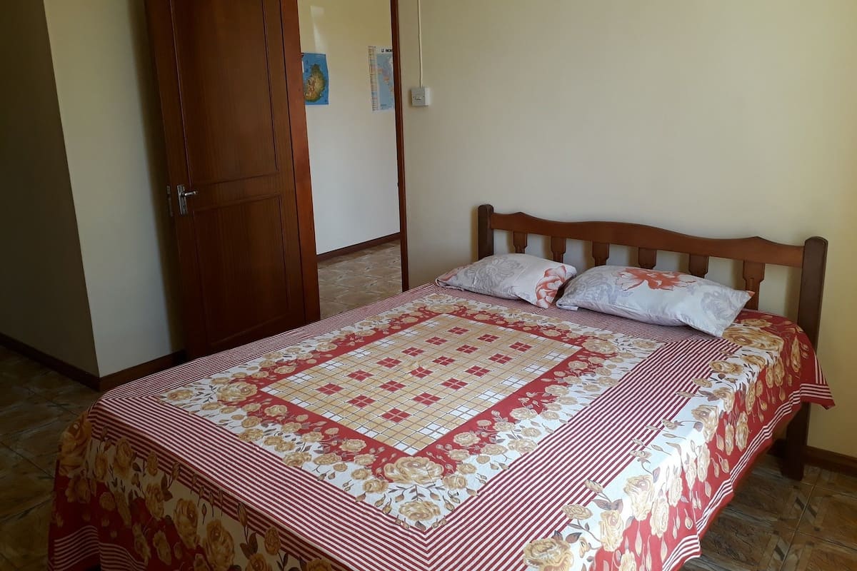 A bedroom with a bed, wooden headboard, and a door.