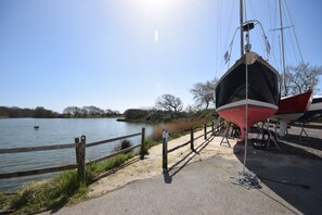 En træbrygge der strækker sig ud i en rolig sø, med både fortøjet i nærheden.