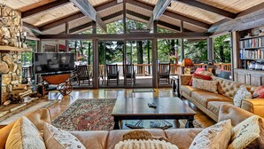 Amplia sala de estar con techo alto, chimenea, televisor y un gran ventanal con vistas a una terraza.