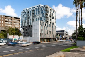 A multi-story hotel with a modern design, featuring balconies, large windows, and a parking area with cars. - La Quinta by Wyndham Parnell Auckland (Auckland)