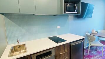 A modern kitchen with a dishwasher, microwave, and a built-in oven. There is a dining area with a table and chairs.