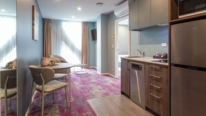 A modern kitchen with a built-in dishwasher, a refrigerator, and a microwave. There is a dining area with a table and chairs. - La Quinta by Wyndham Parnell Auckland (Auckland)