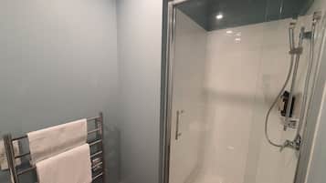 Une douche fermée par des parois en verre, dotée d’un pommeau de douche à main et d’un robinet à main.