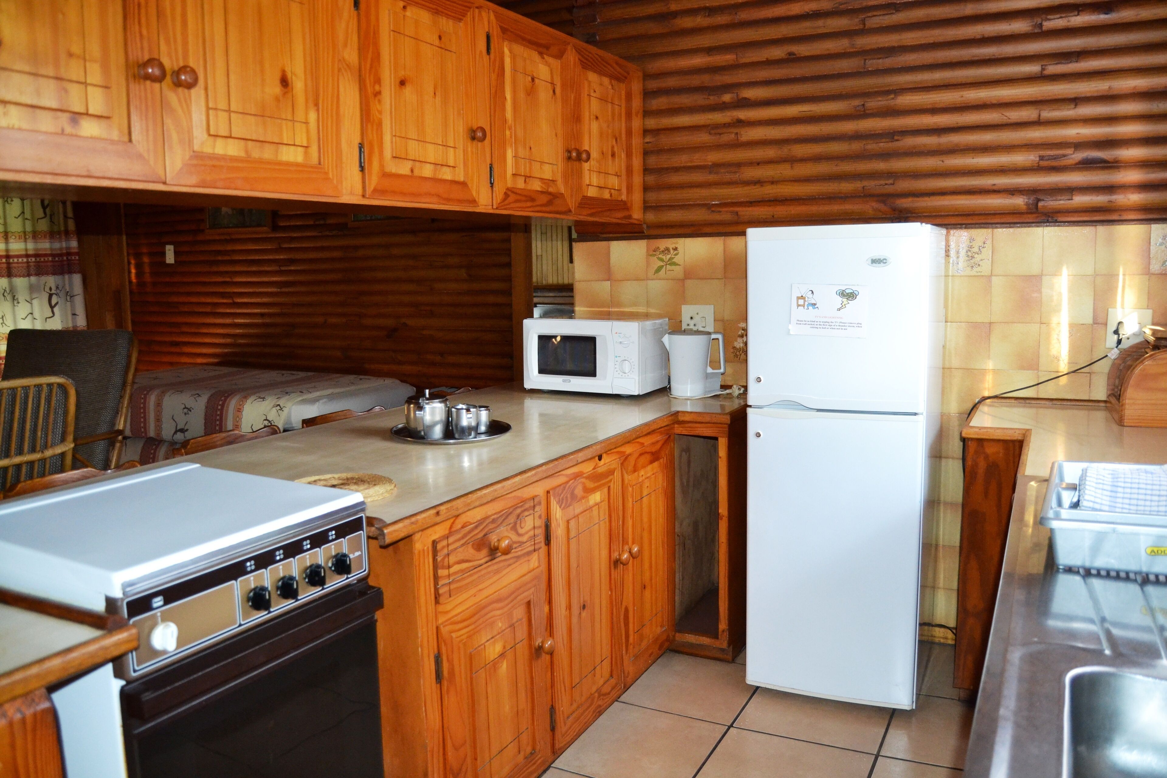 Una cocina compacta con armarios de madera, microondas, refrigerador y estufa.