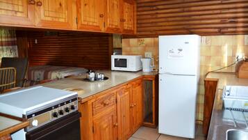 Una cocina compacta con armarios de madera, microondas, refrigerador y estufa.