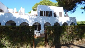 A white building with arched windows and a covered patio area with outdoor seating. - PIVERD DEL GOLF 74 (Pals)