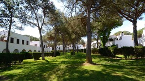 A courtyard with white buildings, trees, and well-maintained grass. - PIVERD DEL GOLF 74 (Pals)