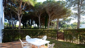 A patio with a white table and chairs, surrounded by a hedge and trees. - PIVERD DEL GOLF 74 (Pals)