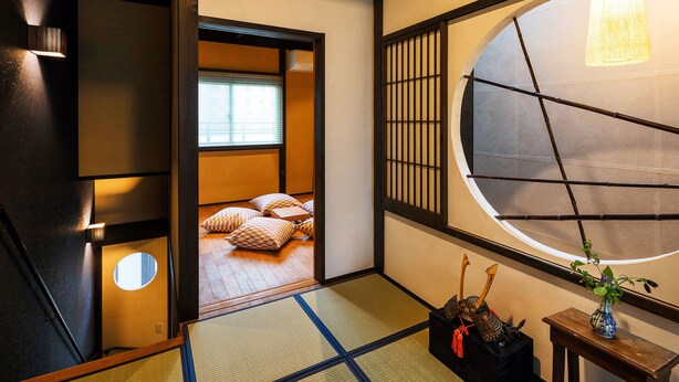 A traditional Japanese room with tatami flooring, a shoji screen door, a tatami mat in the center, and a small table with a vase and decorative items. - Holiday home Nijo Sikibu An Kyoto (Kyoto)
