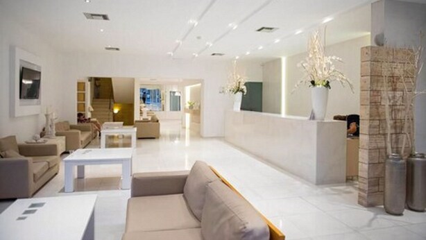 A modern hotel lobby with a reception desk, seating area, and a staircase leading to another floor. - Thalia Hotel (Rhodes)