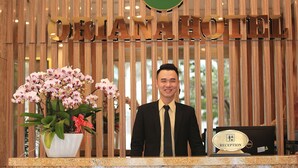 A hotel reception desk with a sign reading "ORIENTAL HOTEL" and a reception area with a potted orchid plant. - Oriana Hotel (Hanoi)