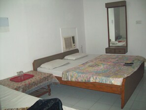 A single bedroom with a bed, a small table with a tray, a mirror, and a heater. - Hotel Majors Den (New Delhi)