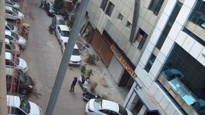Vista de la calle con autos estacionados, un edificio con un letrero que dice 'SITIO DEPORTIVO' y una persona caminando.