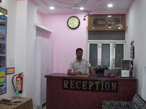 A reception desk with a clock and a framed picture on the wall. - Hotel Majors Den (New Delhi)