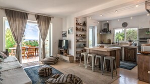 Ein großzügiger Wohnbereich mit großem Fenster, einer Couch und einem Fernseher.