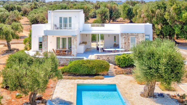Ein modernes, zweistöckiges Haus mit Pool, Außenbereich und Blick auf die umliegende Landschaft.