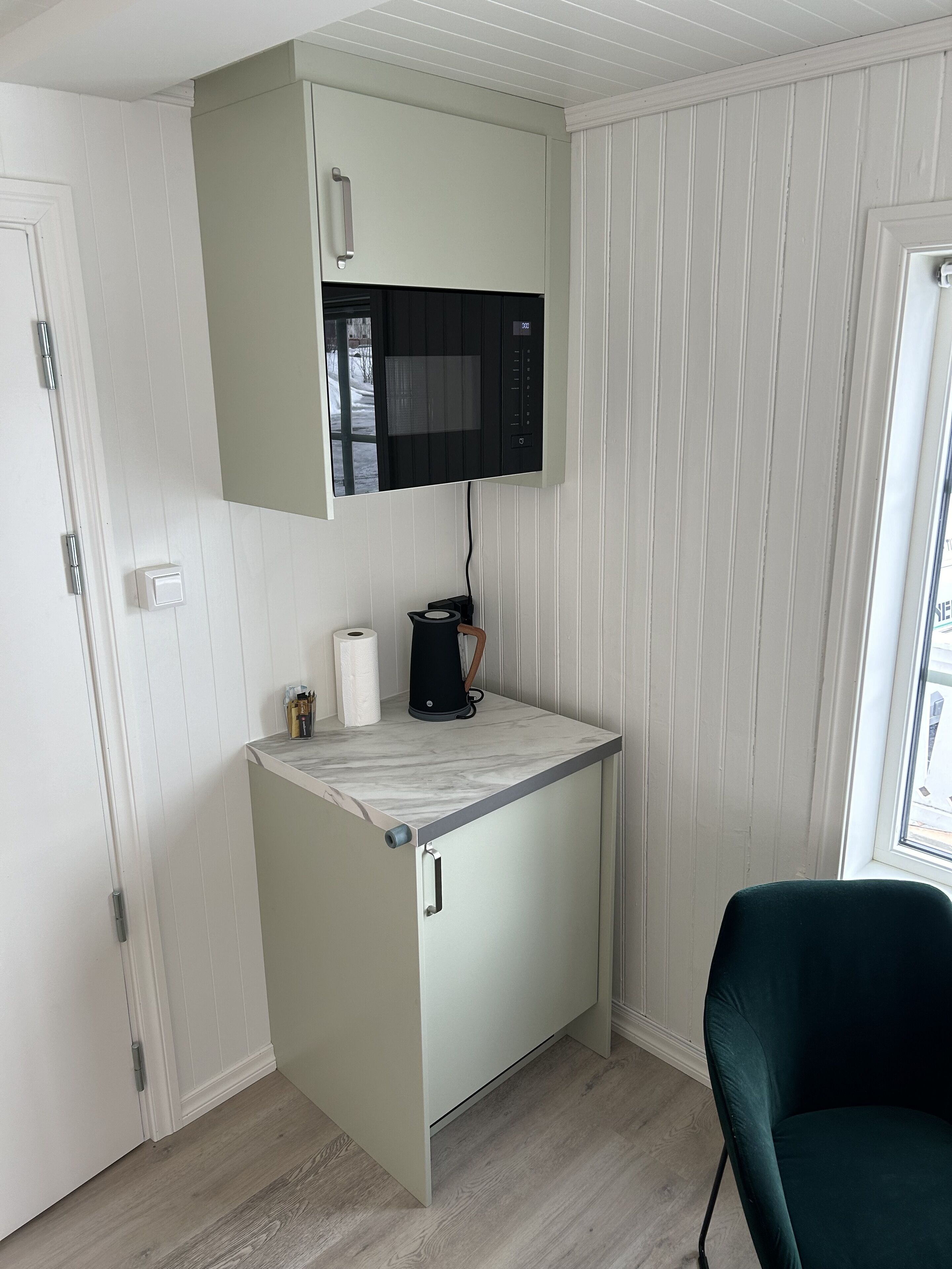 A compact kitchen with a built-in microwave, a coffee maker, and a small countertop.
