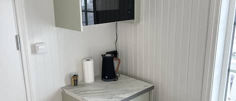 A compact kitchen with a built-in microwave, a coffee maker, and a small countertop.