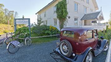 Un coche antiguo estacionado frente a una casa con un letrero que dice "Finsnesgaard".